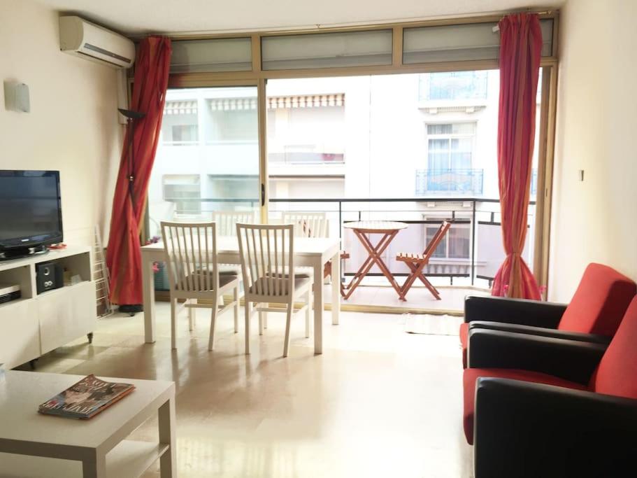 - un salon avec une table, des chaises et une grande fenêtre dans l'établissement Cannes 2pièces Croisette Martinez, à Cannes