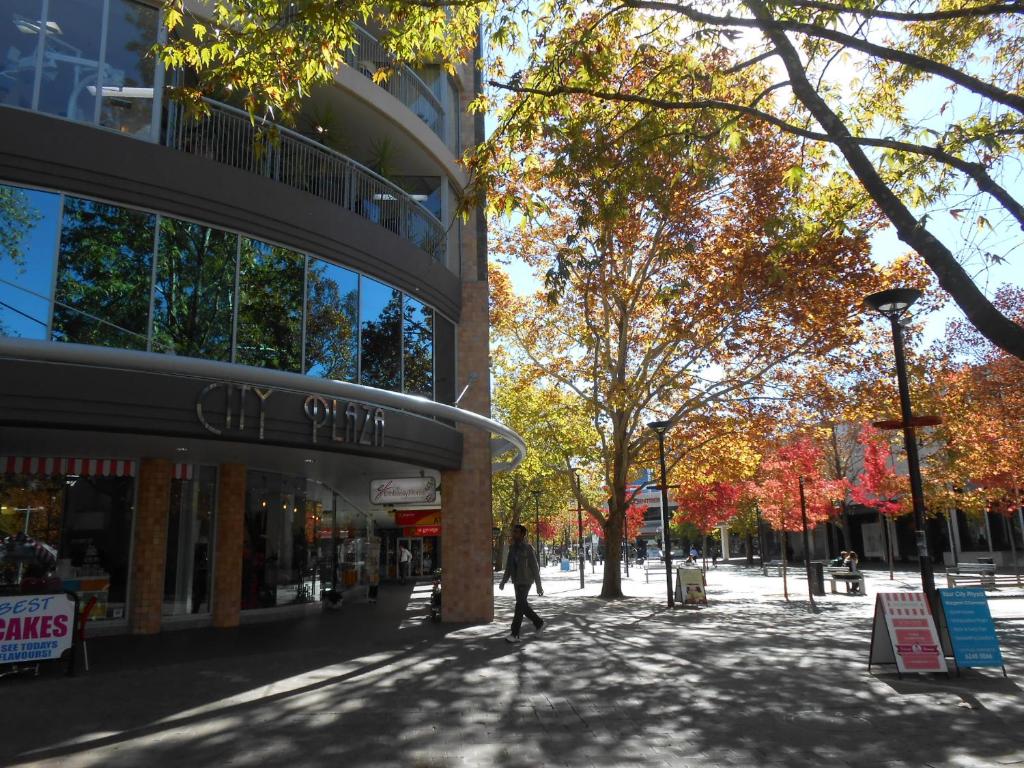 a person walking down a street in front of a building at City Plaza in Canberra