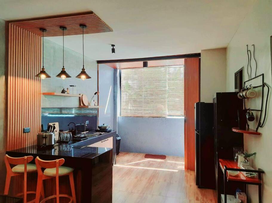 Eine Küche mit schwarzer Arbeitsplatte und orangefarbenen Barhockern in der Unterkunft Maison Tres with Dipping Pool, billiards, airhockey, videoke and netflix and chill in Antipolo