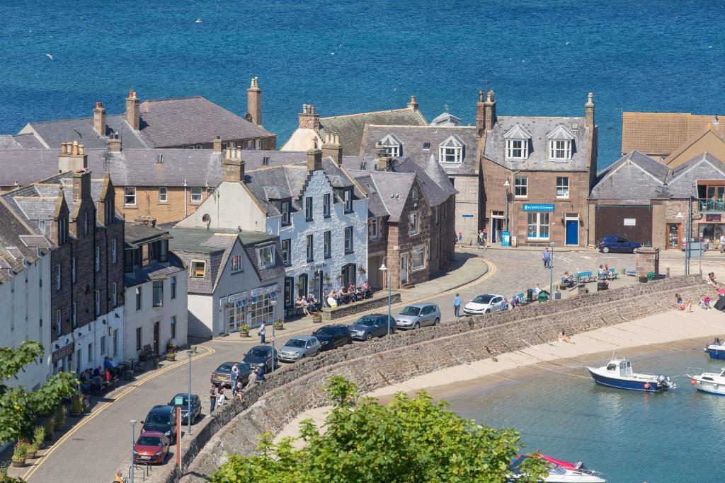 a town with cars parked on a street next to the water at The Ship Inn in Stonehaven