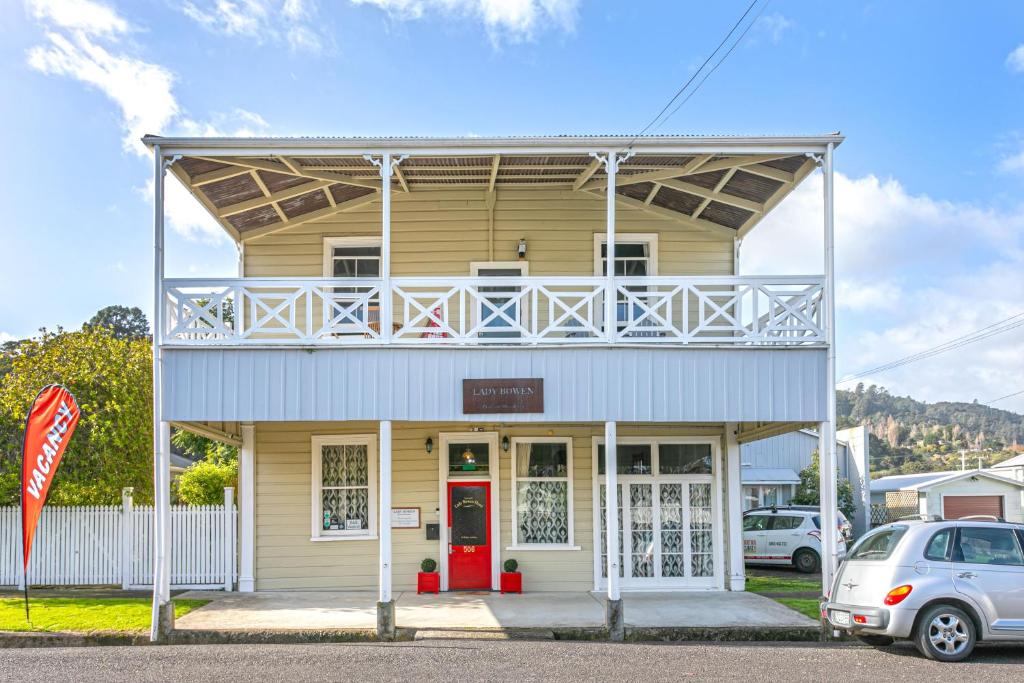 a yellow building with a balcony and a red door at Lady Bowen Bed & Breakfast in Thames