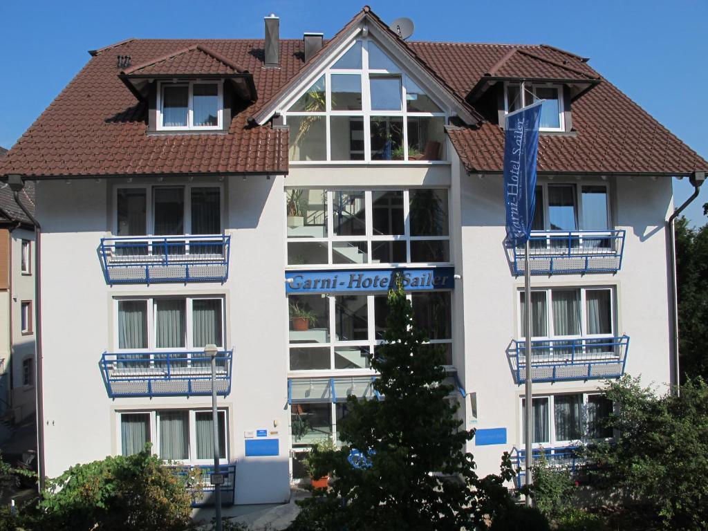 Garni-Hotel Sailer & Hotel Sailer´s Villa في روتويل: مبنى ابيض كبير بالبلكونات الزرقاء