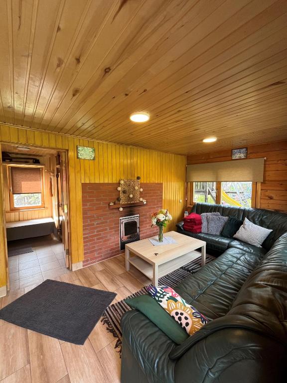 a living room with a leather couch and a table at Cozy Forest Cabin in Kadaga