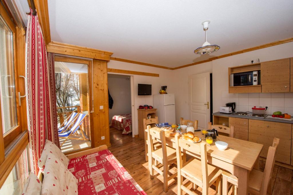 a kitchen and dining room with a table and chairs at Résidence Goélia Le Balcon des Neiges in Saint-Sorlin-dʼArves