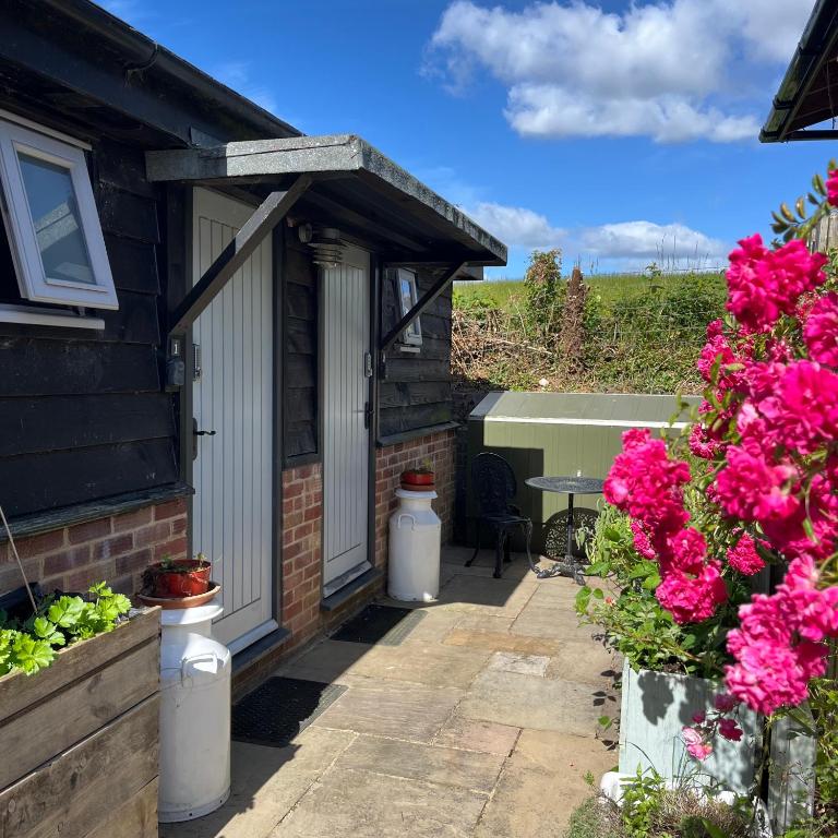 a patio with pink flowers and a house at Bull Farm Studios in Winchester