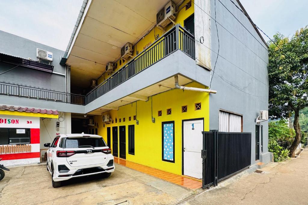 a white car parked in front of a yellow building at Penginapan Dison RedPartner in Bekasi