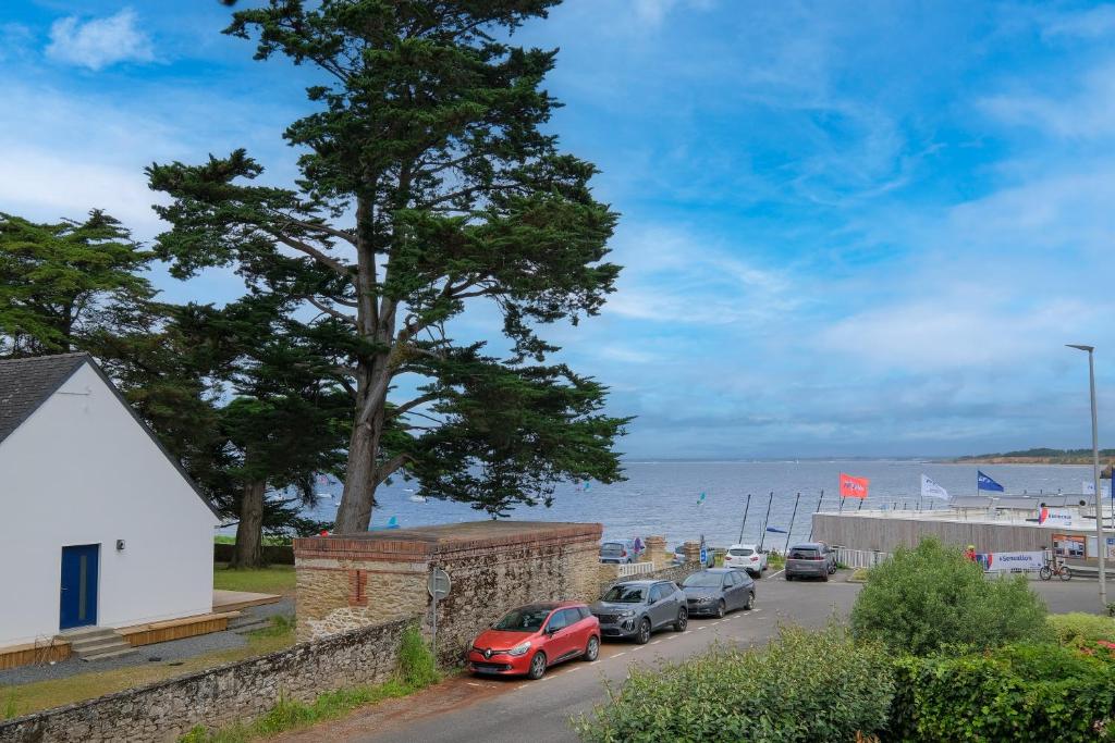 Une rangée de voitures garées dans une rue à côté de l'eau dans l'établissement Villa Bihen - Maison à 50m de la plage, à Pénestin
