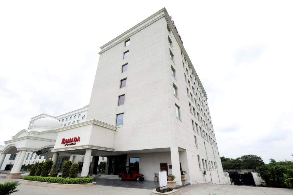 a white building with a miami hotel at Ramada by Wyndham Lucknow Hotel and Convention Center in Lucknow