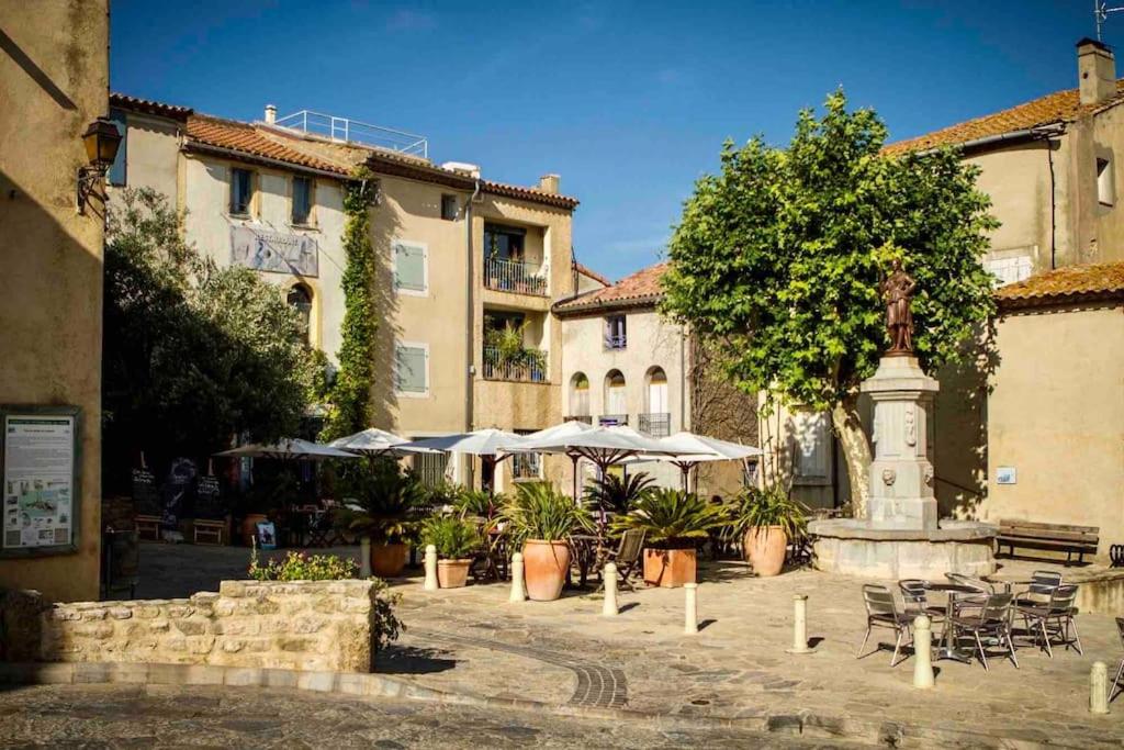 une cour avec une fontaine, des tables et des parasols dans l'établissement Maison Bages d'Aude proche étang, à Bages