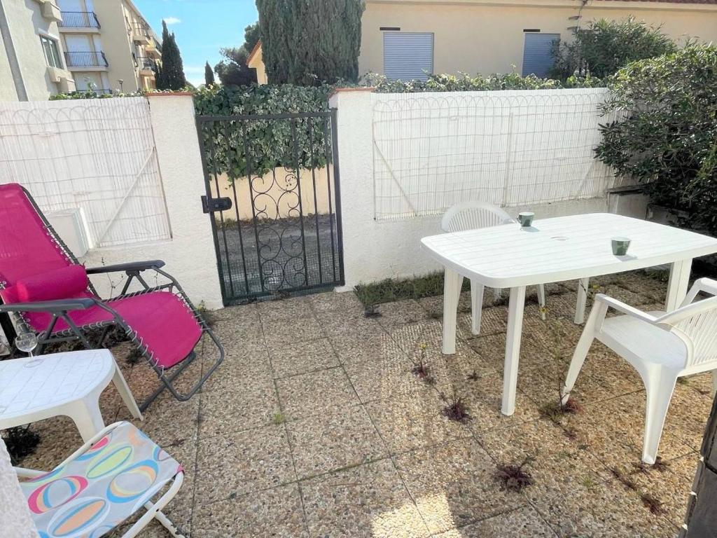 une table et des chaises blanches devant une clôture dans l'établissement Maison 2 pièces 4 couchages ARGELES SUR MER AR000-011, à Argelès-sur-Mer