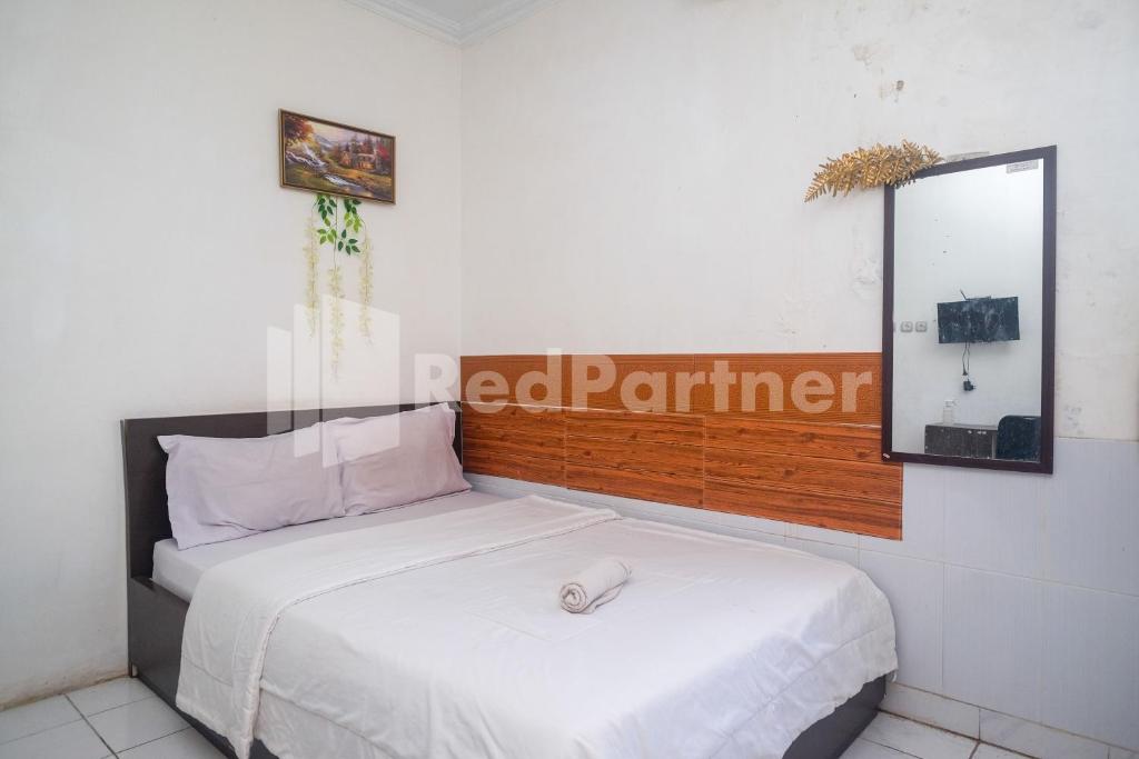 a bedroom with a white bed with a mirror at Griya Jasmine Syariah Seturan RedPartner in Yogyakarta