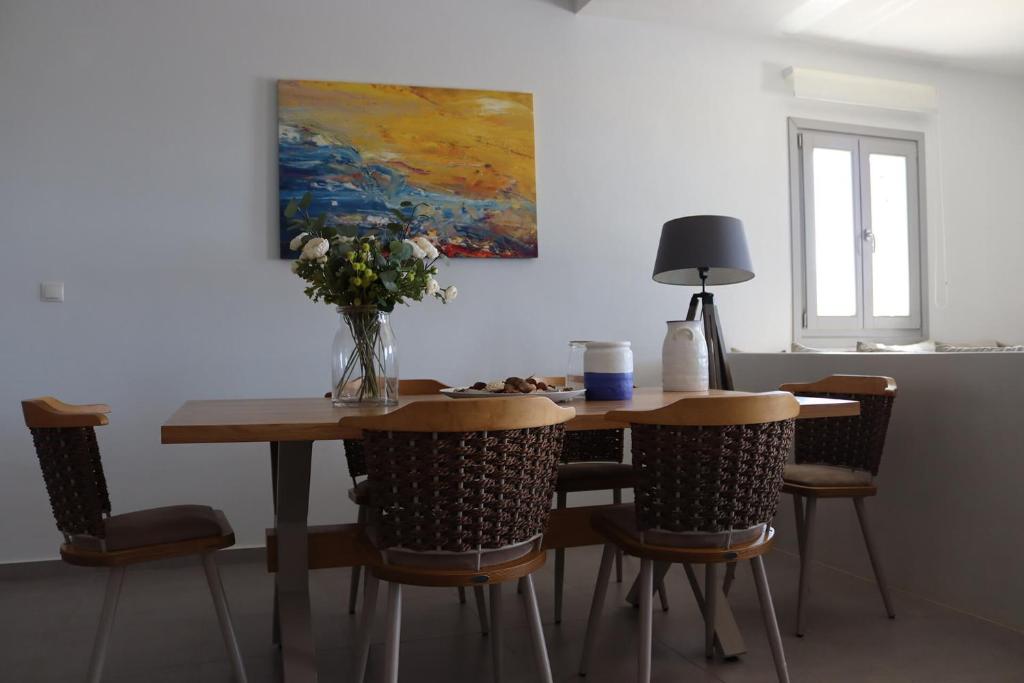 a dining room table with chairs and a vase of flowers at Antigoni Villas in Gavrio