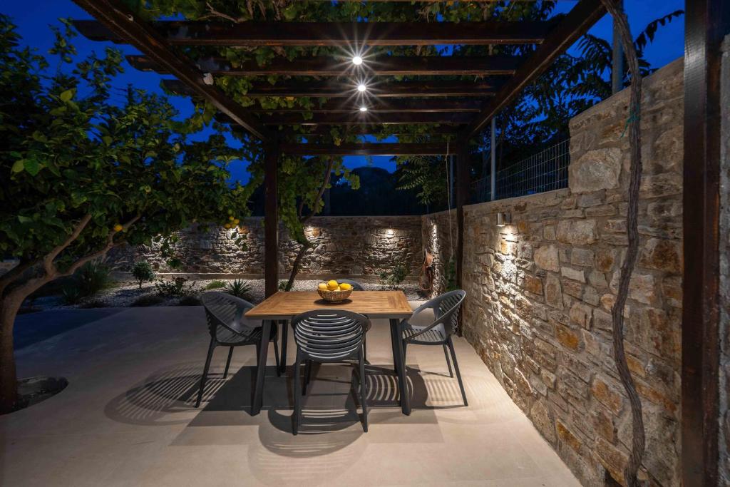 a table and chairs on a patio with a stone wall at Perla's Luxury Apartments in Livadi