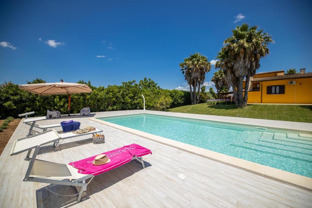 une piscine avec deux chaises et un parasol dans l'établissement Villa Esmeralda, à Taviano