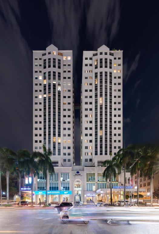 two tall white buildings at night with cars in a parking lot at Somerset Hoa Binh Hanoi in Hanoi