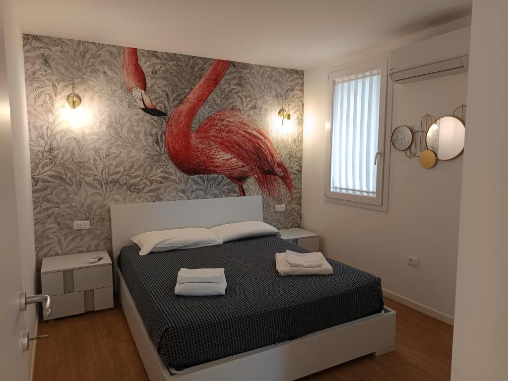 a bedroom with a bed with a red flamingo painting on the wall at L'Alba dei Pescherecci in Chioggia