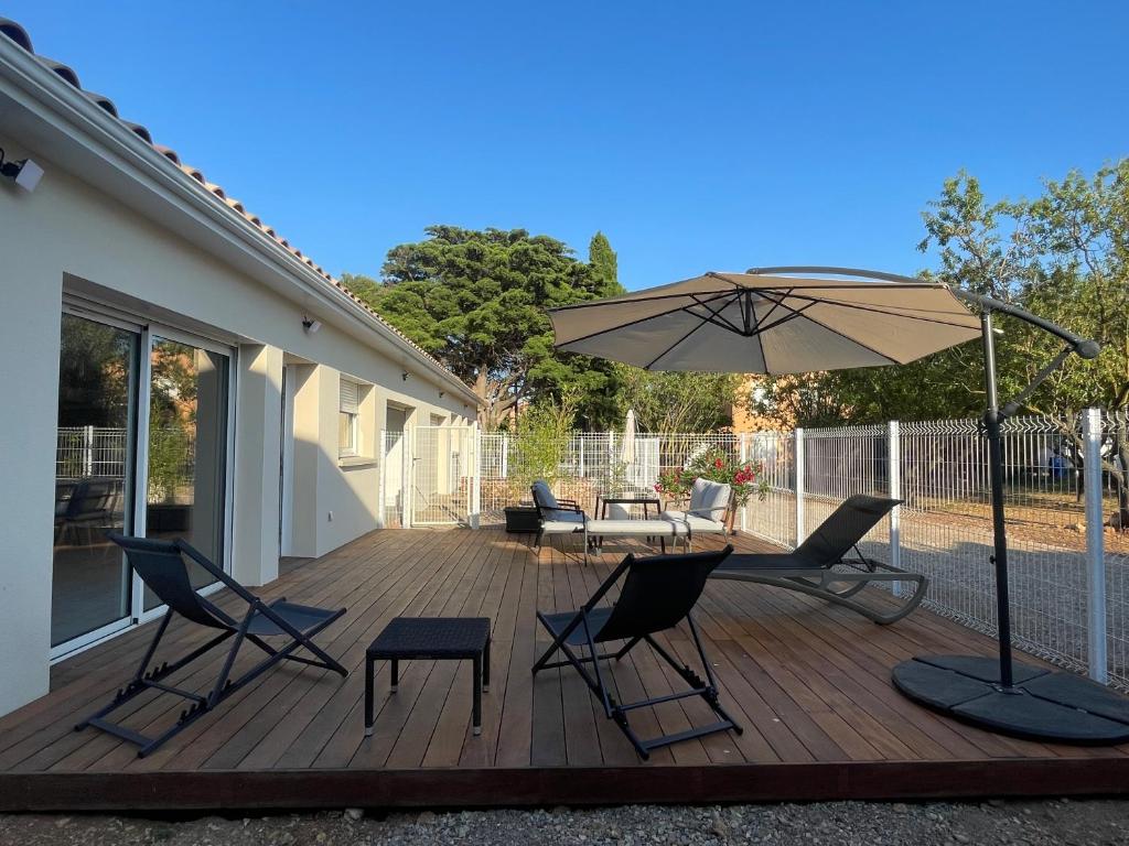 une terrasse en bois avec des chaises et un parasol dans l'établissement Clos des Amandiers, à Balaruc-les-Bains