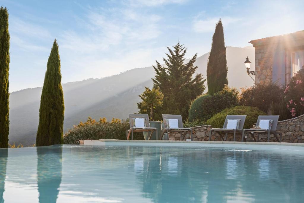 ein Swimmingpool in einem Hof mit Stühlen und Bäumen in der Unterkunft Villa La Genestière - Familienoase und Golfertraum mit Infinity-Pool und 180-Grad-Panoramablick bis zum Meer in Seillans