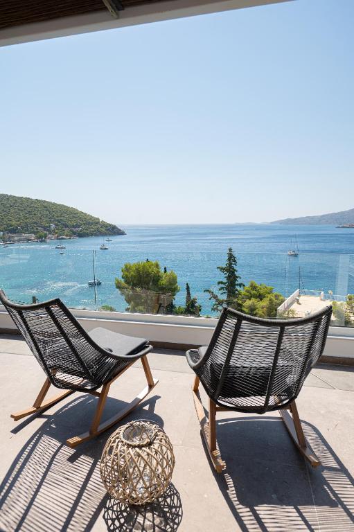 two chairs on a balcony with a view of the water at SEMIRAMIS Luxury Apartments in Poros