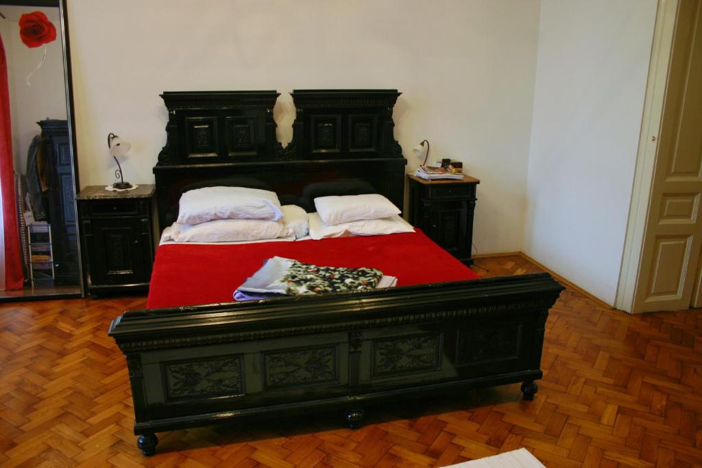 a bedroom with a black bed with a red blanket at Pepermint in Osijek