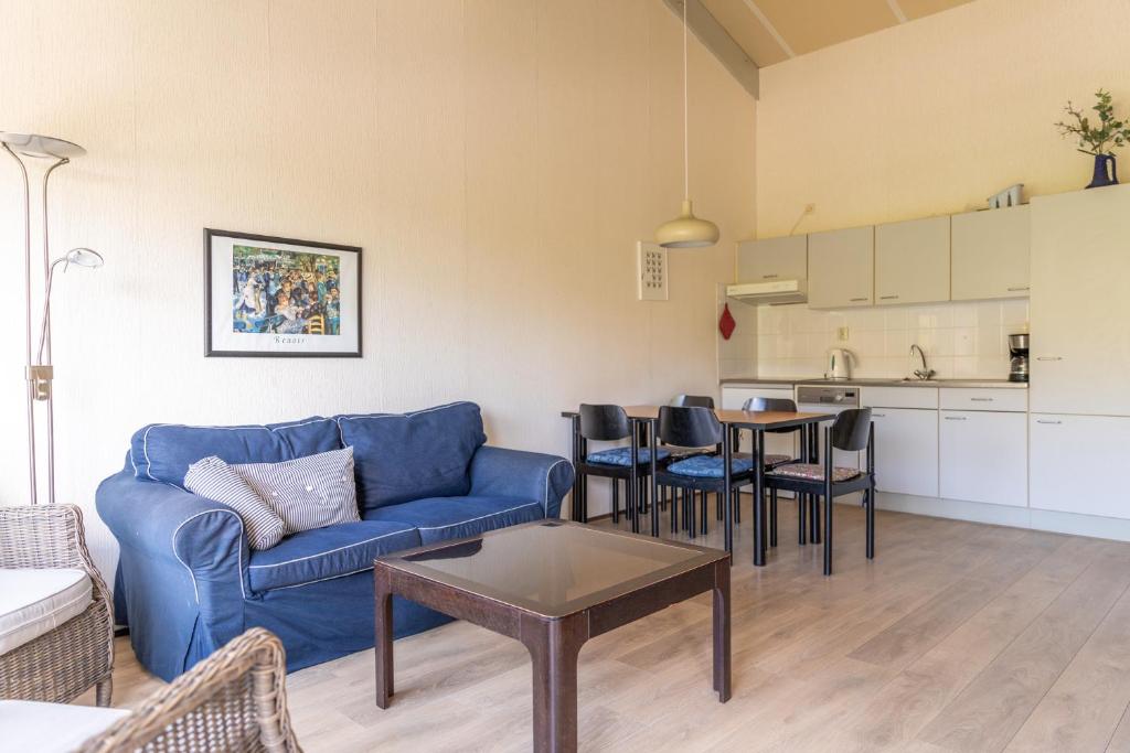 a living room with a blue couch and a table at Beach appartement 40 in Callantsoog