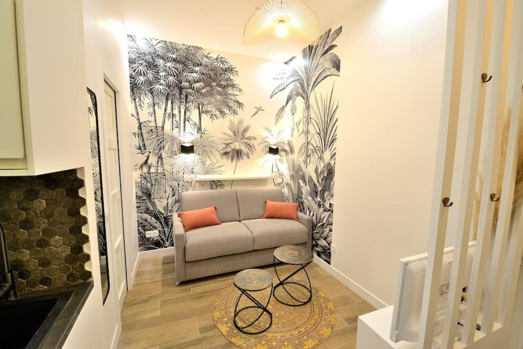 - un salon avec un canapé et une fresque murale de palmiers dans l'établissement Tiny cosy studio NAMASTAY in trendy Canal St Martin area, à Paris