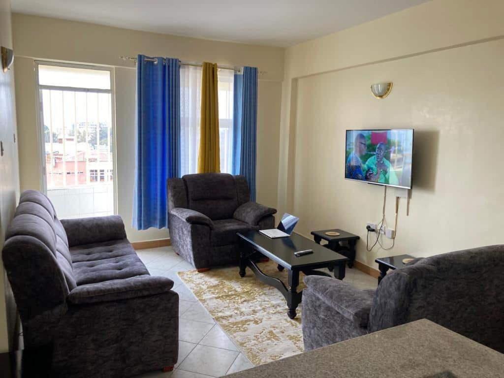 - un salon avec des canapés, des chaises et une télévision dans l'établissement Thika Furnished Apartments, à Thika