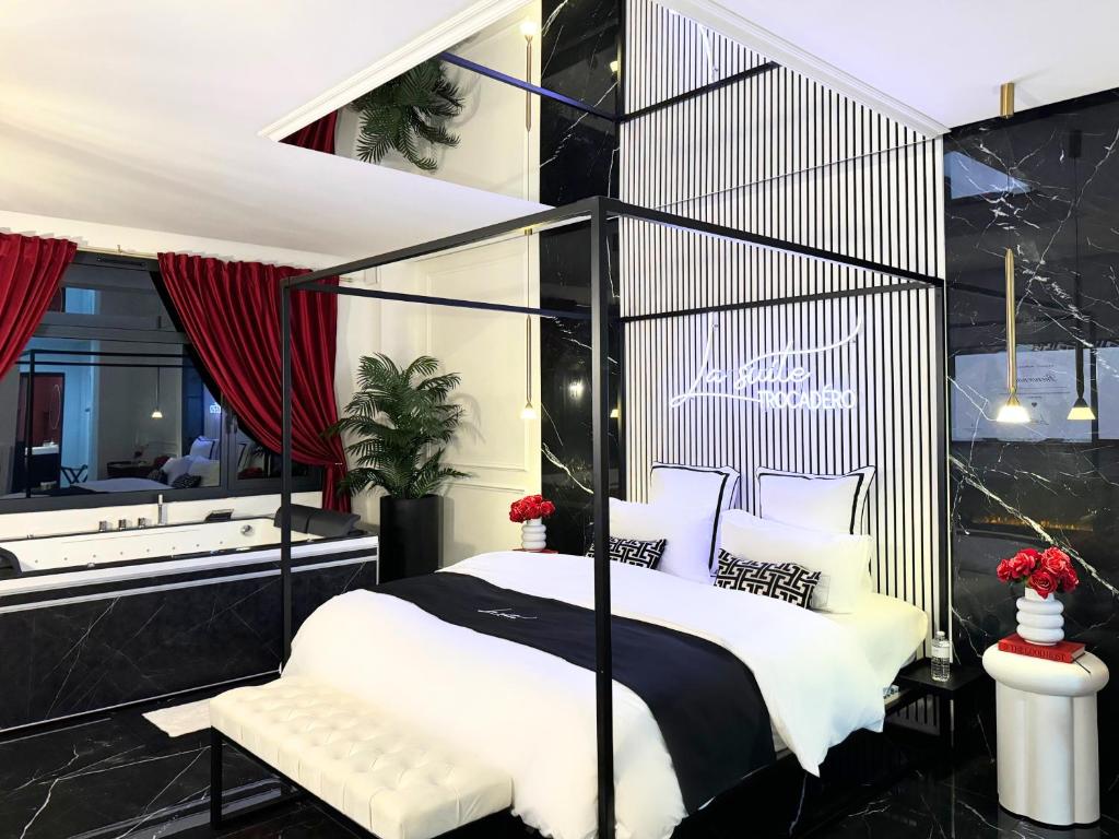 una camera con letto bianco e nero e un bagno di La Suite Trocadéro - Jacuzzi privatif a Parigi