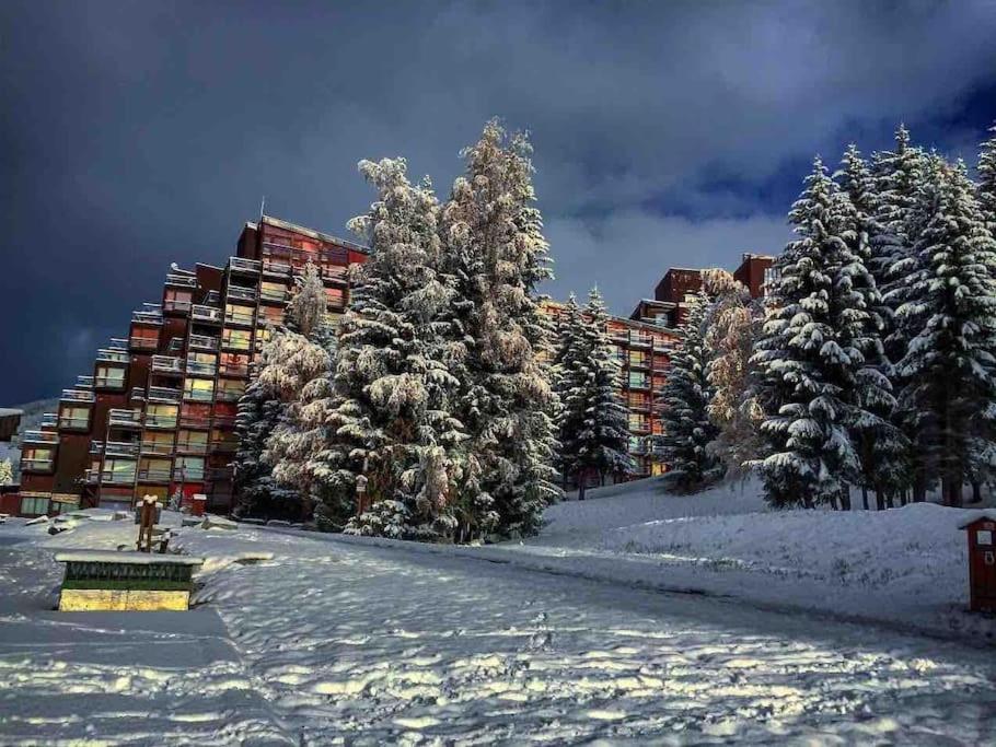 un bâtiment avec des arbres enneigés devant lui dans l'établissement Petit Appart Cosy 4 pers en plein coeur d'Arc 1800, à Bourg-Saint-Maurice