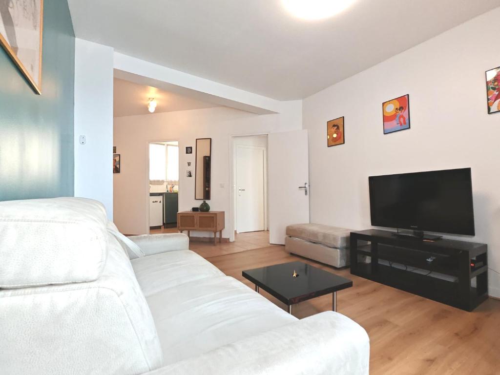 Il comprend un salon doté d'un canapé blanc et d'une télévision à écran plat. dans l'établissement 3 Pièces près de Paris - Métro 4, à Saint-Ouen