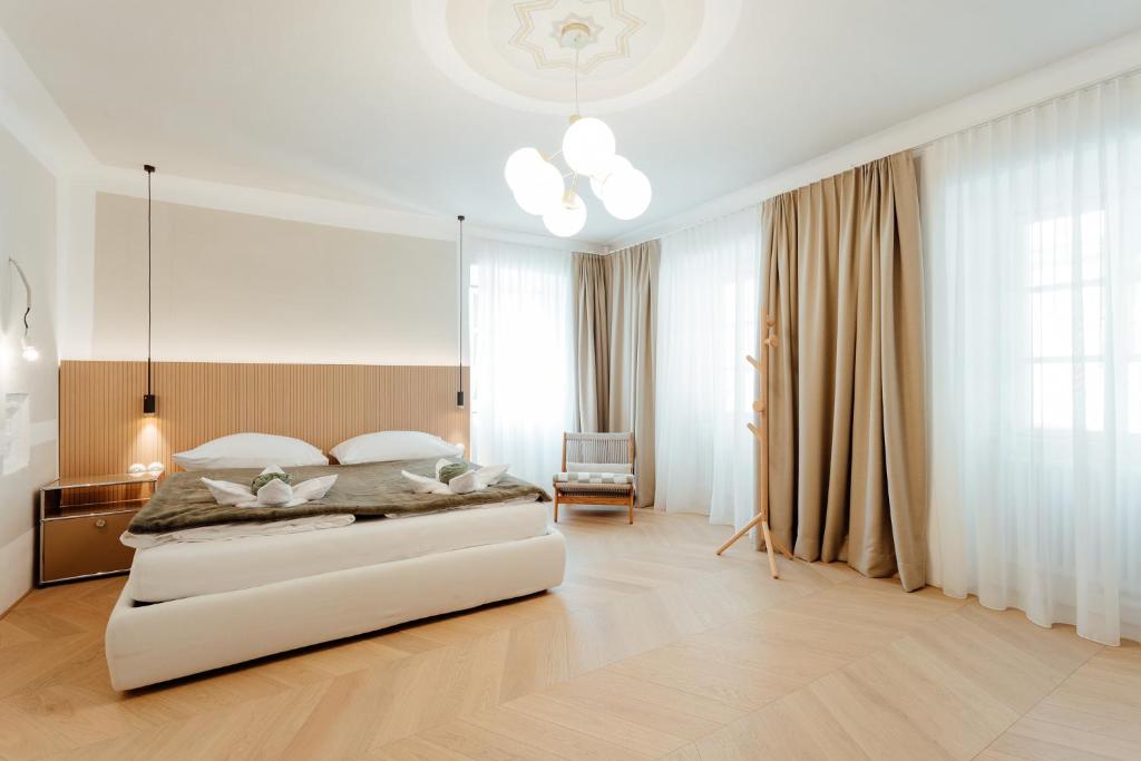 a bedroom with a large white bed and a chair at Apartmánový dom BiSou - Trojičné námestie in Banská Štiavnica