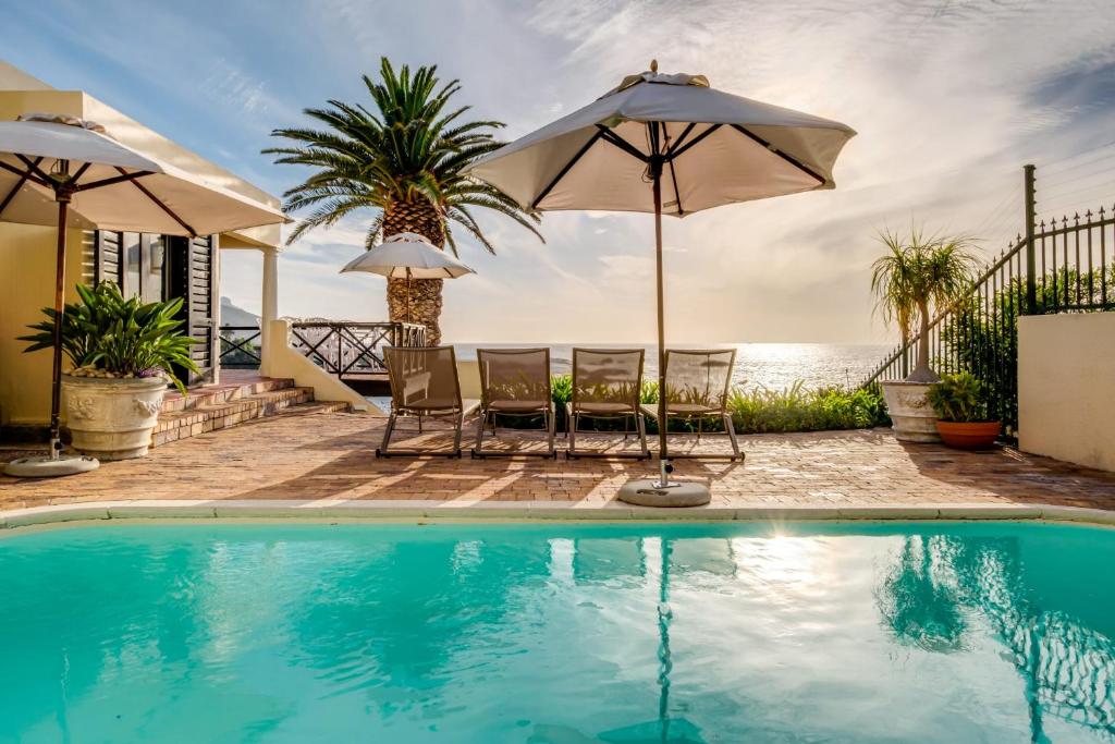 a swimming pool with two chairs and an umbrella at Camps Bay Terrace Lodge in Cape Town