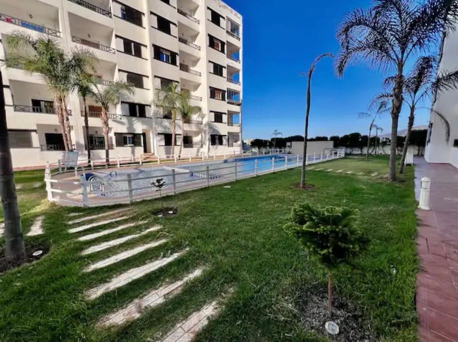 a building with stairs and palm trees in the grass at Appartement à louer Complexe City Center in Oued Laou