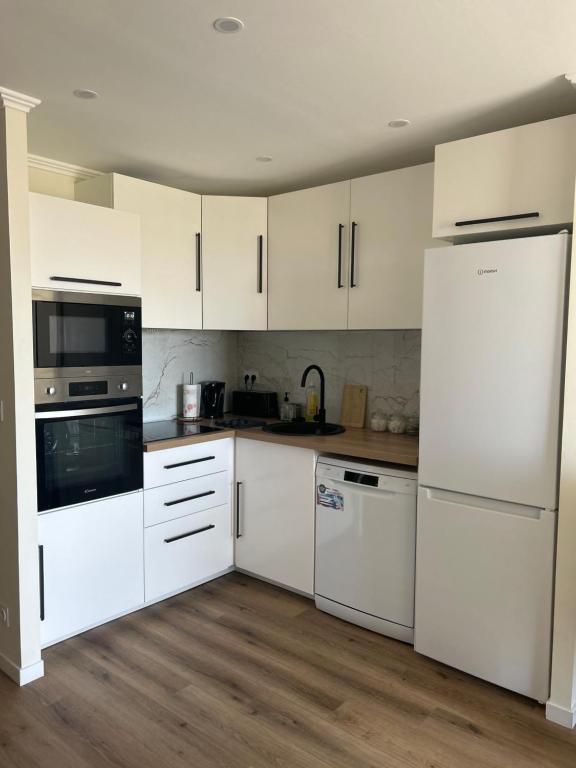 une cuisine avec des appareils électroménagers blancs et des armoires blanches dans l'établissement Plage, stade et parking privé dans la résidence, à Marseille