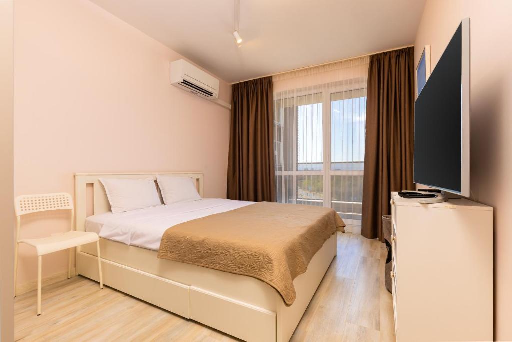 Un dormitorio con una cama y un televisor de pantalla plana. en Bright and Cozy 1BD Flat in Plovdiv with Parking by Flat Mаnager, en Plovdiv