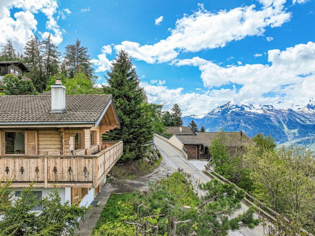 a log home with a porch and mountains in the background at Chalet Le Loup- le Renard et la Belette by Interhome in Nendaz