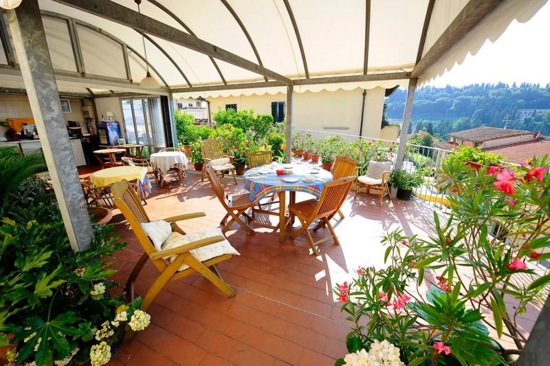 eine Terrasse mit einem Tisch, Stühlen und Blumen in der Unterkunft Albergo Villa Sorriso in Fiesole