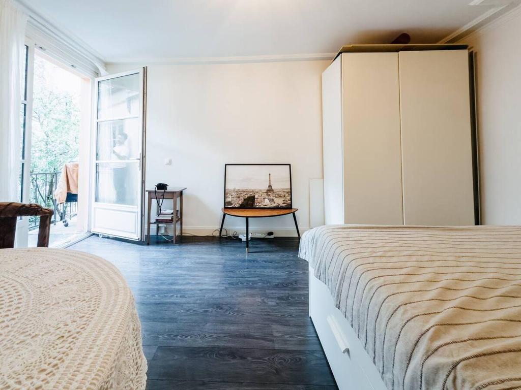 une chambre blanche avec un lit et une commode dans l'établissement studio au calme, à Paris