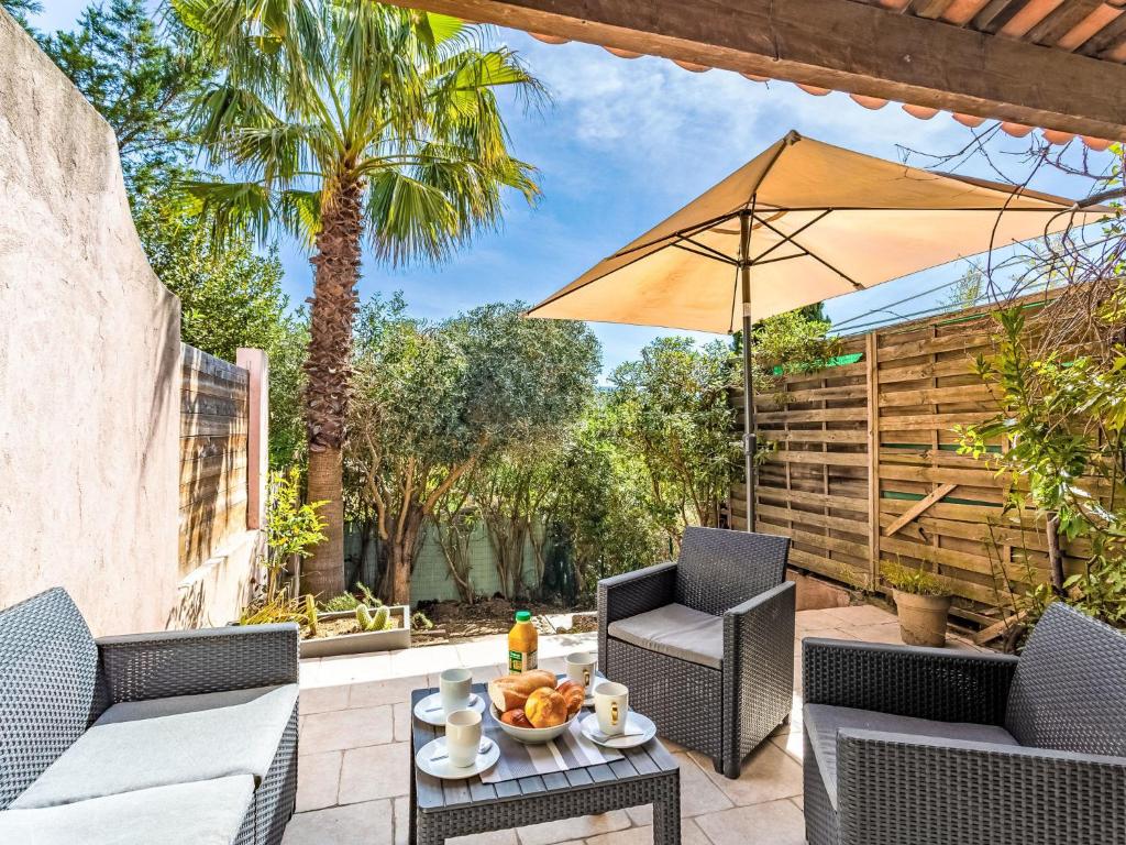 un patio avec deux chaises et un parasol dans l'établissement Holiday Home Le Hameau de Gassin by Interhome, à Gassin