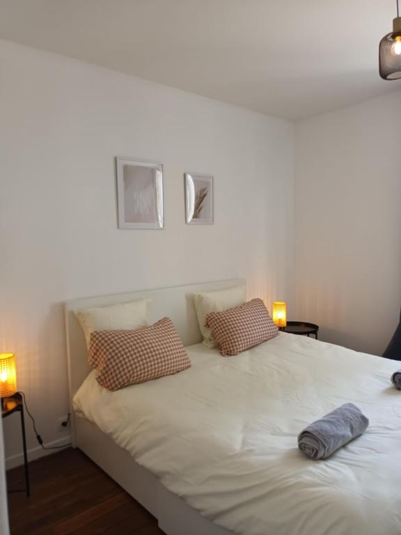 un lit blanc avec deux oreillers dessus dans l'établissement Superbe appart à 15 min à pied du stade de France, à Aubervilliers