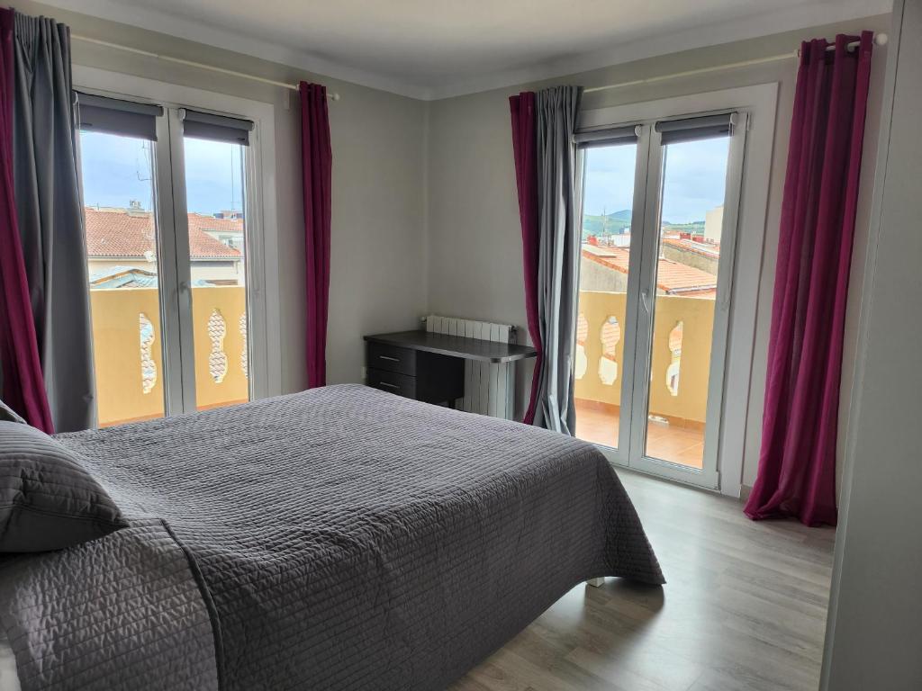 a bedroom with a bed and large windows at Piso centrico amplio-luminoso in Zarautz