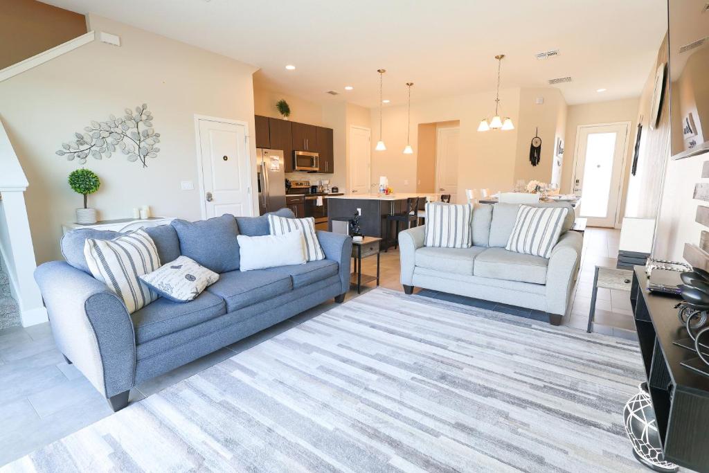 a living room with two blue couches and a kitchen at 216 Oasis Magic 4BD Villa 5 Min to Disney Magic in Loughman