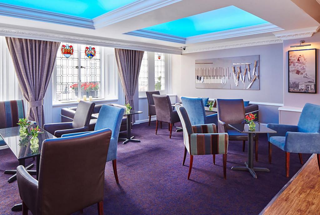 ein Wartezimmer mit Stühlen und Tischen und Fenstern in der Unterkunft Lancaster Gate Hotel in London