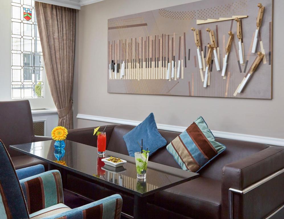 ein Wohnzimmer mit einer Couch und einem Tisch in der Unterkunft Lancaster Gate Hotel in London