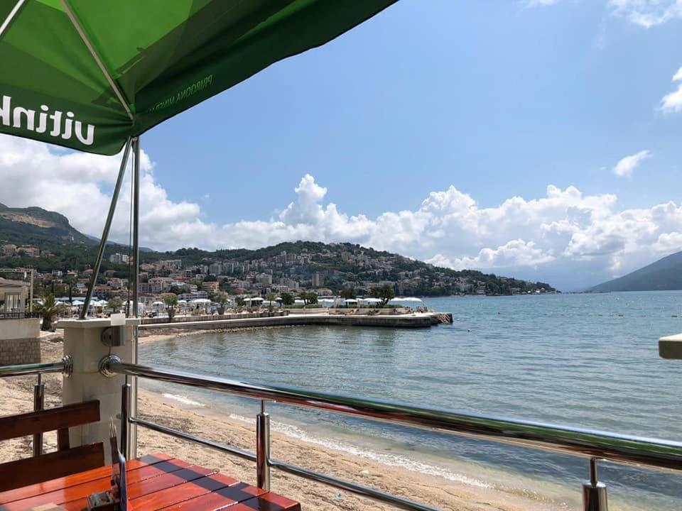 a beach with a green umbrella and the water at Igalo Vuke in Igalo