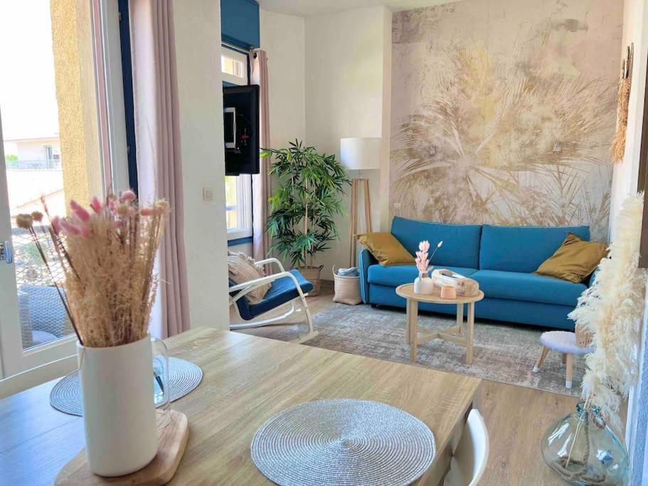 un salon avec un canapé bleu et une table dans l'établissement Saint Maurice -T2 accès privé mer YourHostHelper, à Palavas-les-Flots