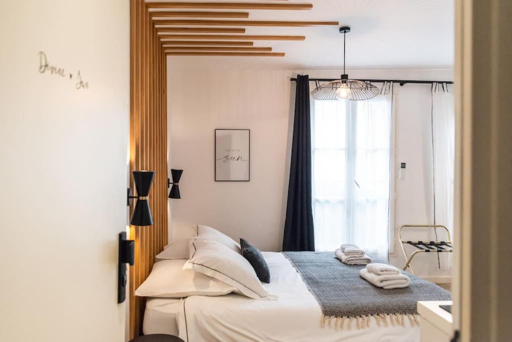 une chambre avec un lit avec des oreillers blancs et une fenêtre dans l'établissement Elégant studio DIVINE SUN quartier Canal St Martin, à Paris
