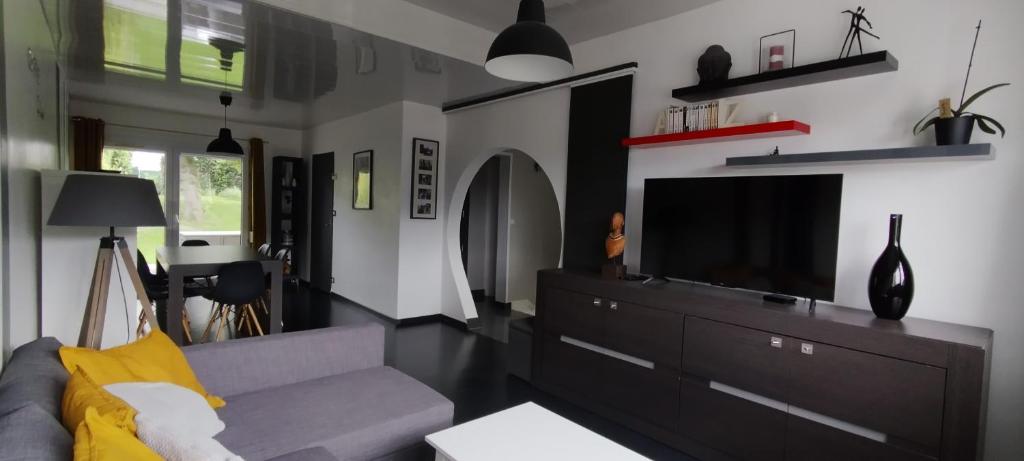 un salon avec un canapé et une télévision dans l'établissement Les Aubépines, à Rancennes