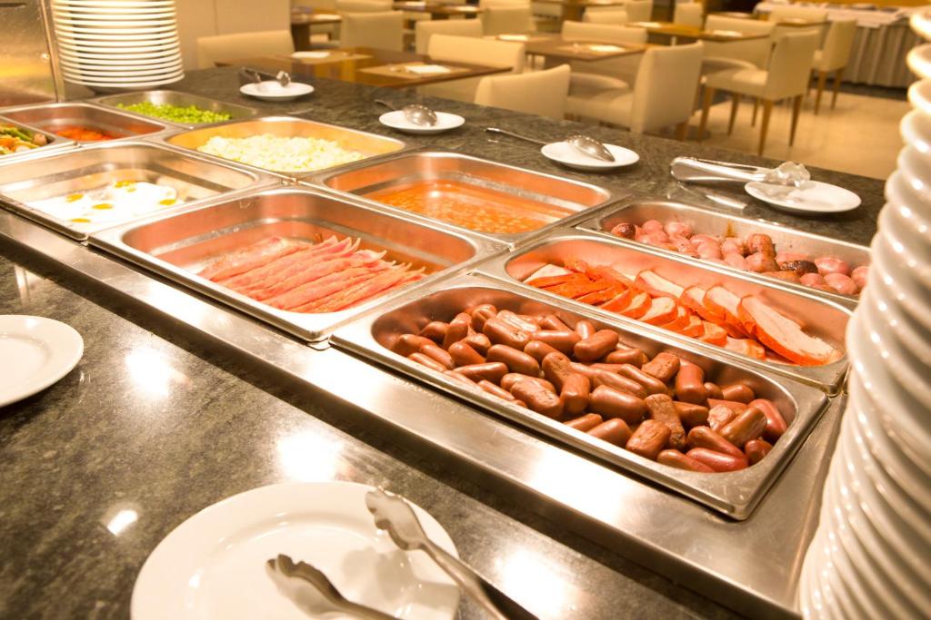 a buffet line with trays of different types of food at Hotel Albufera in Alfafar