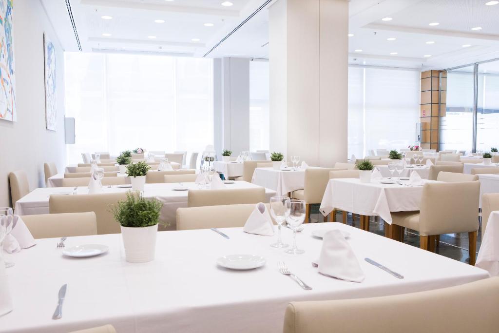 a dining room with white tables and chairs at Hotel Albufera in Alfafar